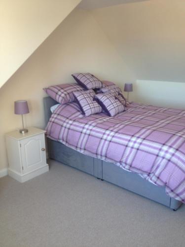 - une chambre avec un lit violet et des oreillers dans l'établissement Acorn Apartment, à Dufftown