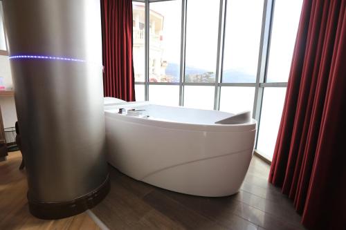 a white bath tub sitting in front of a window at City Palace Hotel in Ohrid