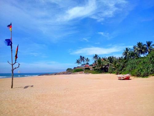 a beach with a flag and a pole in the sand at Sri Lancashire Guest House in Bentota