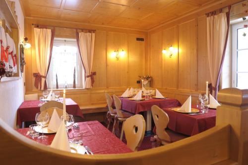 a dining room with red tables and chairs and a window at Alpstyle Hotel Albolina Wellness & Beauty in Canazei