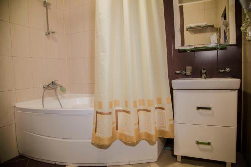 y baño con bañera y cortina de ducha. en Uyut Vnukovo Hotel, en Vnukovo