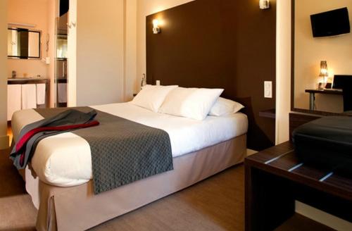 サン・レオナール・ド・ノブラにあるLogis Le Relais Saint Jacquesの大型ベッドとテレビが備わるホテルルームです。