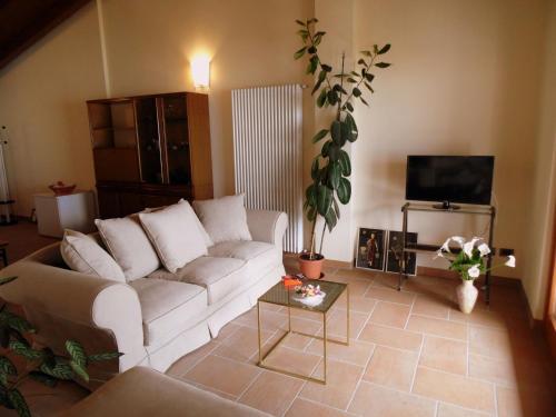 a living room with a white couch and a tv at Belvilla by OYO Belvedere in Marone