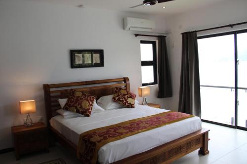a bedroom with a bed and a large window at Surfers Cove Apartments in Bel Ombre