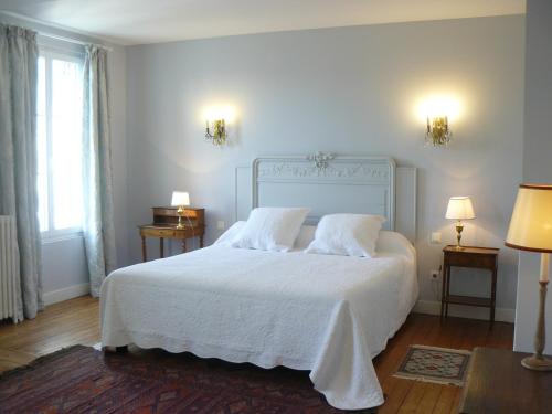 a bedroom with a white bed with two lamps and two tables at La Maison de Saumur in Saumur