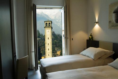 a room with two beds and a clock tower through a window at Hotel San Lorenzo Chiavenna in Chiavenna