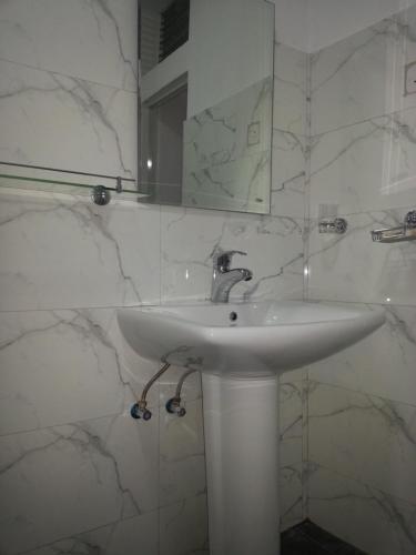 a white bathroom with a sink and a mirror at Forest View Homestay in Kandy
