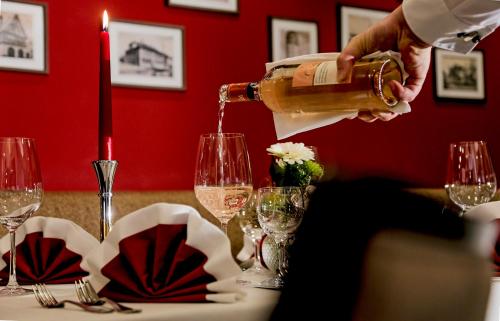 a person pouring wine into a table with wine glasses at Adler Hotel & Restaurant Groß-Gerau in Groß-Gerau