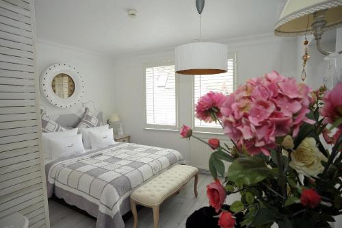 a bedroom with a bed and a vase of pink flowers at Hotel Ottaviano in Świnoujście