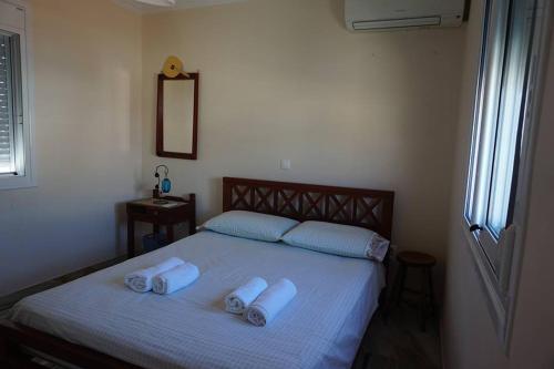 a bedroom with a bed with three towels on it at Artemis House in Karpathos