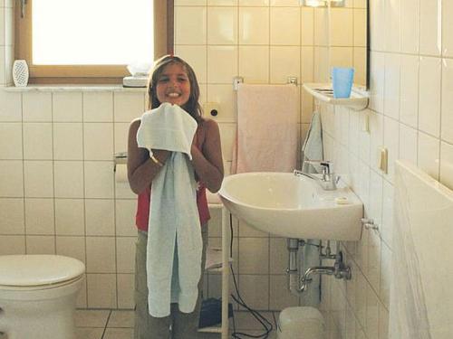 Mała dziewczynka stojąca w łazience trzymająca ręcznik w obiekcie Detached single-storey bungalow with south-facing terrace w mieście Uslar