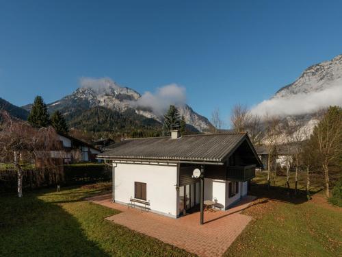 a small white house with mountains in the background at Holiday home in Groebming near ski areas in Gröbming