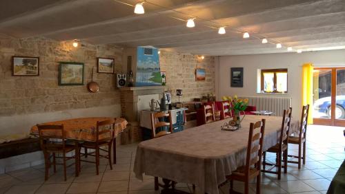 a dining room with two tables and chairs and a kitchen at La ferme du Grand Faubourg in Pont-de-Vaux