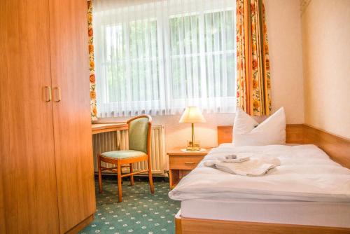 シュトールベルク・イム・ハルツにあるHaus Irmchenのベッド、デスク、窓が備わるホテルルームです。