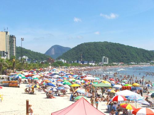eine große Menschenmenge an einem Strand mit Sonnenschirmen in der Unterkunft Hotel Pousada Guaratuba in Guaratuba