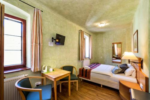 a bedroom with a bed and a desk and a table at Pension U Hada in Český Krumlov