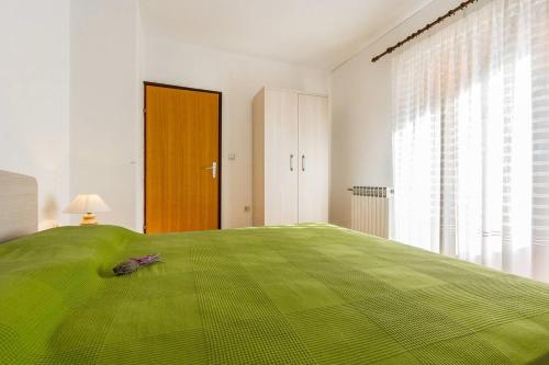 een slaapkamer met een groot groen bed en een raam bij Apartments Valbandon in Fažana
