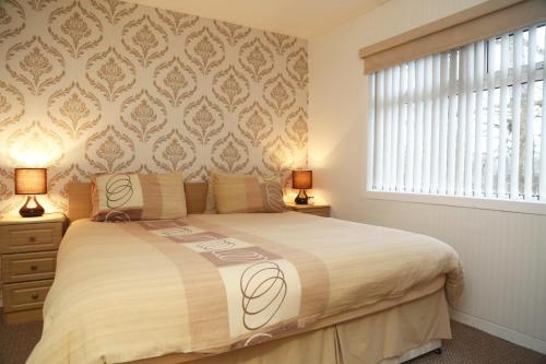 a bedroom with a bed with two lamps and a window at Edenmore in Ardrossan