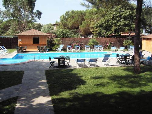 a swimming pool with tables and chairs next to at Hotel Anfora in Castiglione della Pescaia