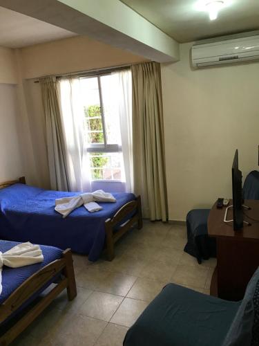 a room with two beds and a tv and a window at Amoblados Neuquen ALTO COMAHUE SHOPPING in Neuquén
