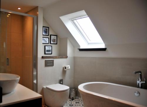 a bathroom with a toilet and a tub and a skylight at Marmalade in Portree