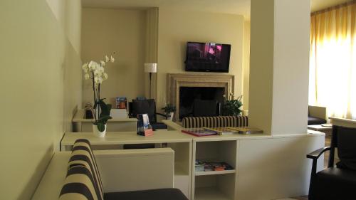 a living room with a desk with a tv and a fireplace at Hotel Romeo in Torri del Benaco
