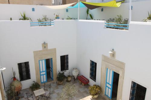 a room with white walls and blue doors and chairs at Dar R'Bat, Maison d'Hôtes de charme in Nabeul