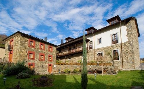 a large stone building with a grass yard in front of it at Hotel y apartamentos rurales L'Anceo in Cibuyo