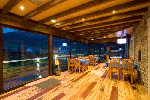 a restaurant with tables and chairs on a wooden floor at Hotel y apartamentos rurales L'Anceo in Cibuyo