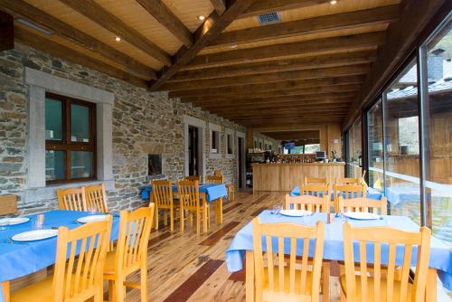 a dining room with blue tables and wooden chairs at Hotel y apartamentos rurales L'Anceo in Cibuyo