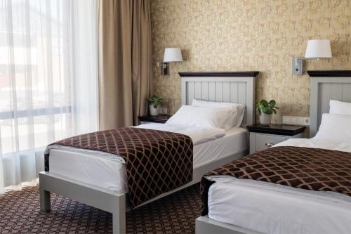 a hotel room with two beds and a window at Hotel Sinchronas in Telšiai