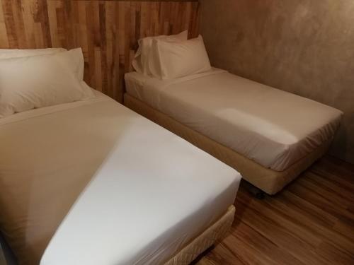 two beds in a small room with white sheets and pillows at The Rise Room in Kuala Terengganu