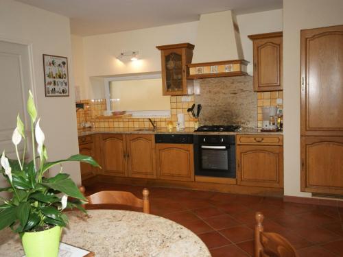 une cuisine avec des placards en bois et une table avec une plante dans l'établissement Holiday Home in Saint-Pompont with Pool, à Saint-Pompont