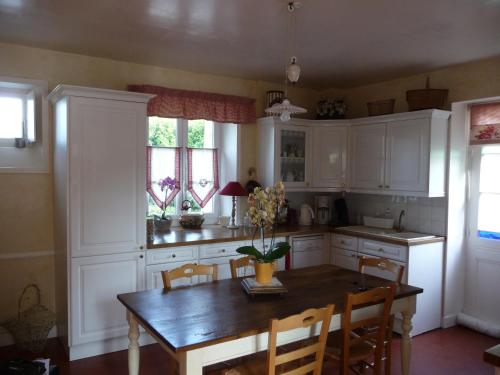 une cuisine avec des armoires blanches et une table en bois dans l'établissement Chambres d'Hôtes La Gloriette, à Ryes