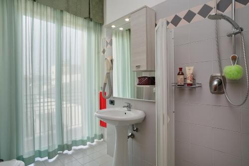 a bathroom with a sink and a shower with a mirror at Residence Margherita in Cattolica