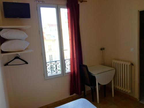 Zimmer mit einem Fenster, einem Schreibtisch und einem Tisch in der Unterkunft Hôtel du Centre in Paris