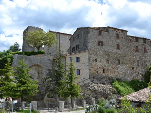 um antigo edifício de pedra com uma torre numa colina em Belvilla by OYO Graceful Apartment with Garden em Petrella Guidi