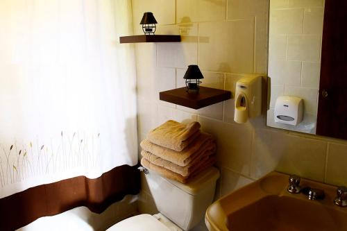 a bathroom with a toilet and a sink and towels at Cabañas & Piscina Rucamalen in Ensenada