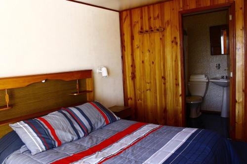 a bedroom with a bed with a wooden head board at Cabañas & Piscina Rucamalen in Ensenada