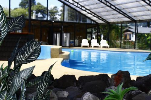a swimming pool in a house with chairs and plants at Cabañas & Piscina Rucamalen in Ensenada