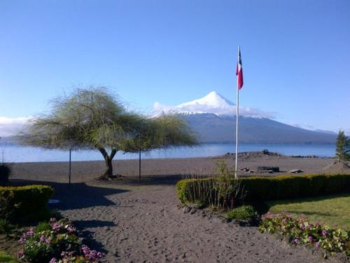 a flag pole on a beach with a mountain in the background at Cabañas & Piscina Rucamalen in Ensenada