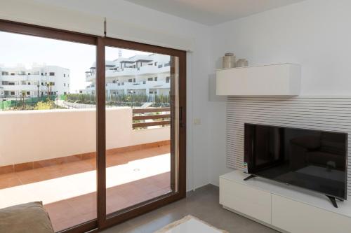 a living room with a flat screen tv next to a window at Mar de Pulpí Las Azucenas by Mar Holidays in San Juan de los Terreros