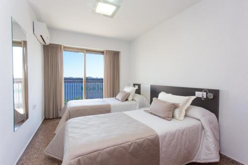 a hotel room with two beds and a large window at Pio XII Apartments Valencia in Valencia