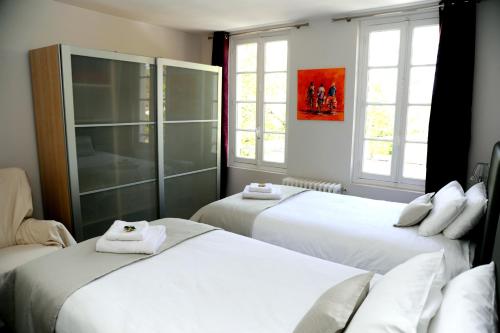 1 dormitorio con 2 camas y 2 ventanas en Face Au Jardin, en Cognac