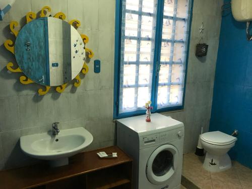 Un baño con lavadora y lavabo. en Acquamarina B&B, en La Maddalena