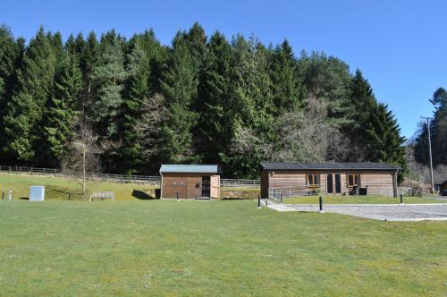 a small wooden building in a field with trees at Tayview Lodges in Pitlochry