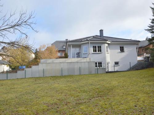 Ein weißes Haus auf einem Hügel mit einem Zaun in der Unterkunft Apartment in Ulmen near the lake in Ulmen