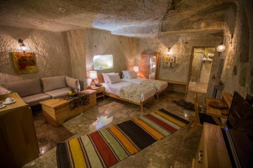 a bedroom with a bed and a couch in a cave at Agarta Cave Hotel in Goreme