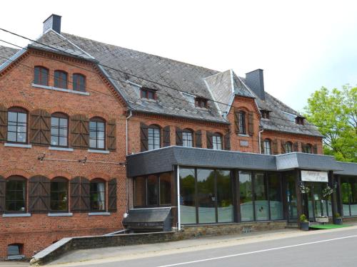 a red brick building with a black roof at Former hotel in Malmedy with indoor swimming pool in Xhoffraix