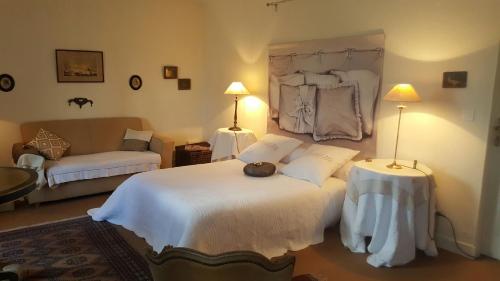 - une chambre avec un grand lit blanc et un canapé dans l'établissement Logis de la Paqueraie, à Saint-Branchs